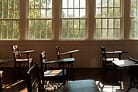 Interior of the restored one-room schoolhouse, showing wooden desks and windows